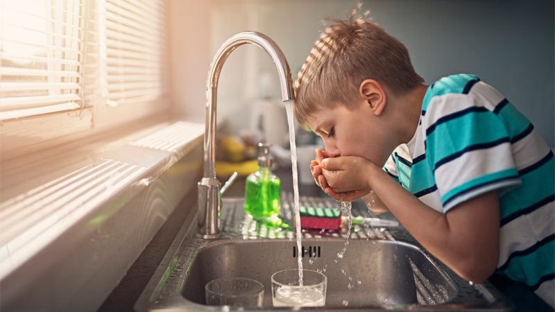 Child drinking from faucet